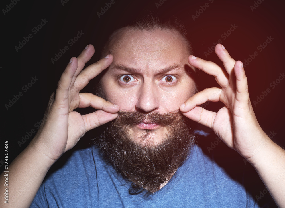 Serious man with beard adjusting his mustaches. Serious man with beard adjusting his mustaches.