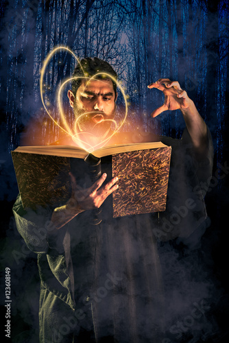 Foto Male sorcerer casting a spell from a magic book as halloween ima