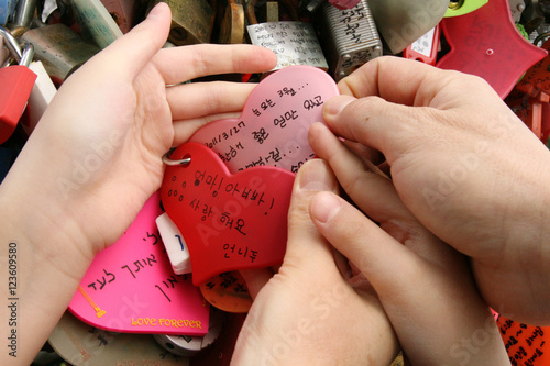 Photography Many love padlocks locked on iron chain and family hands.