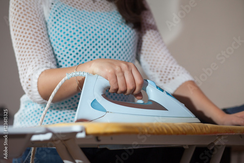 Young woman ironing some clothes (focus on hand)