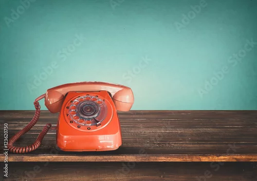 Obraz Stary retro czerwony telefon na stole z rocznika zieleni pastelowym tłem