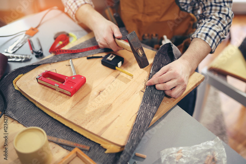 Man upholstering chair in his workshop, measure wooden board