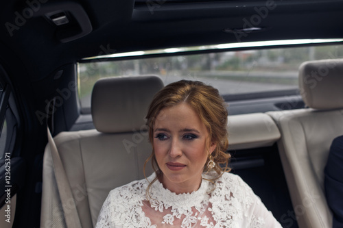 Beautiful bride looks sad driving in the car with groom