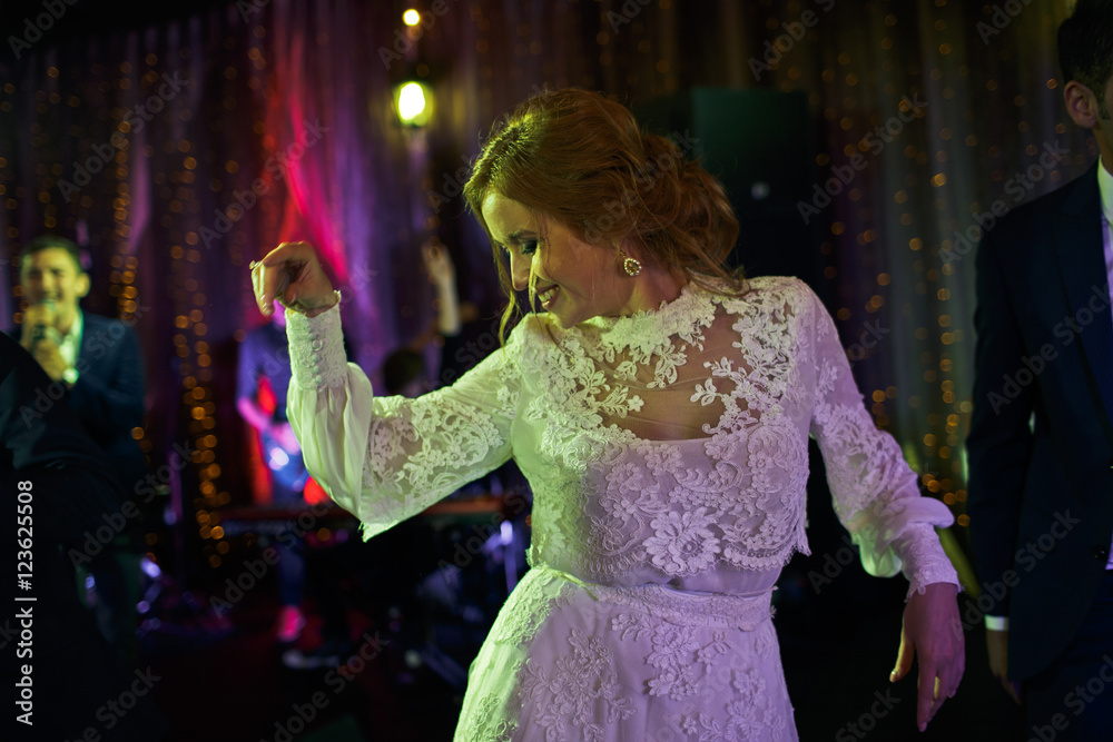 Delicate bride dances alone in the middle of dancefloor