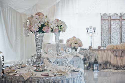 The vases with flowers on the wedding tables © nastasenko