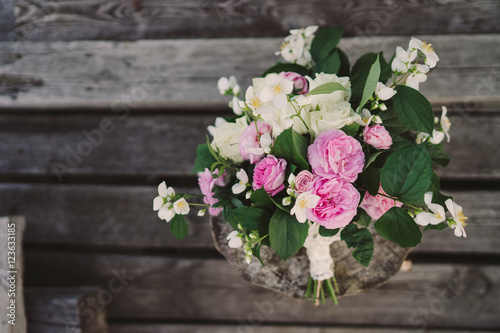 Beautiful bouquet of jasmine and pink garden roses with lace ribbons on old wooden pier