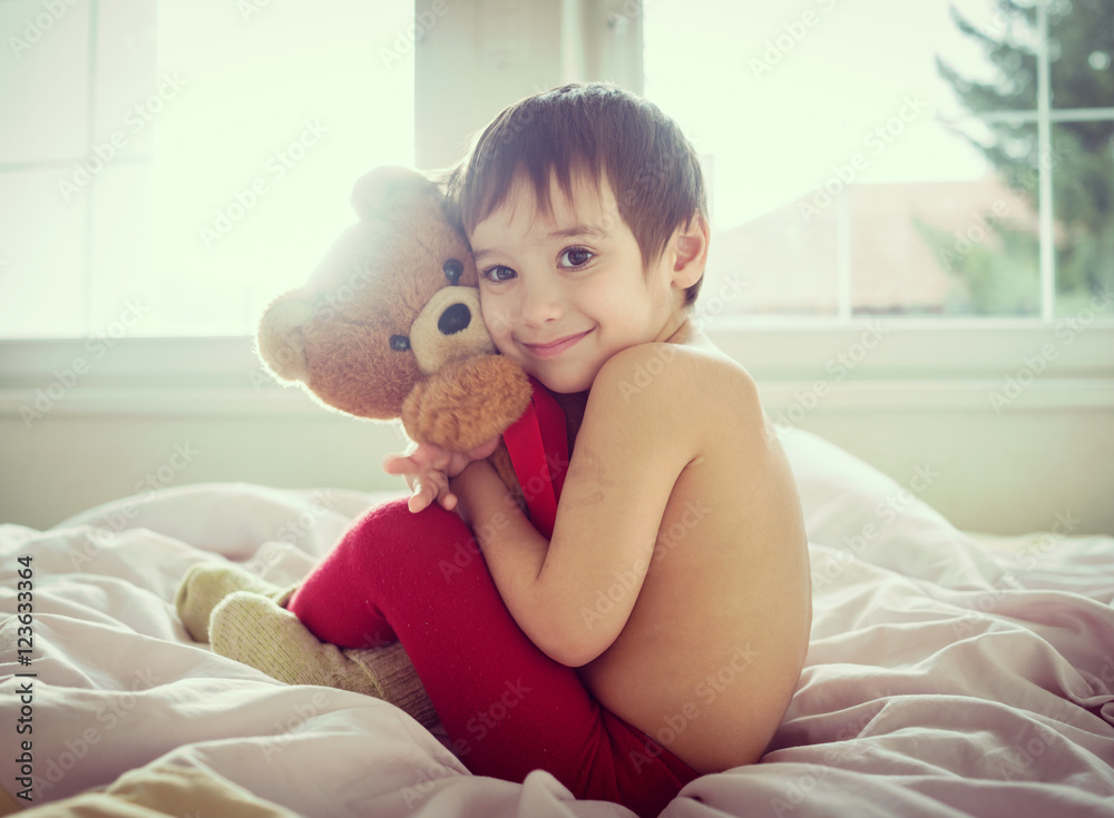 A little cute boy with Teddy bear on the bed A little cute boy with Teddy bear on the bed