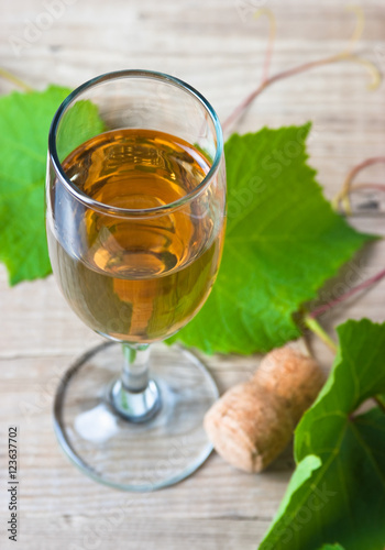 glass of wine and vine on wooden table