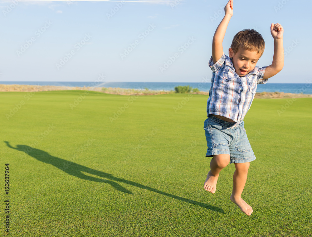 Happy little boy on summer gulf grass terrain having fun and hap Happy little boy on summer gulf grass terrain having fun and hap