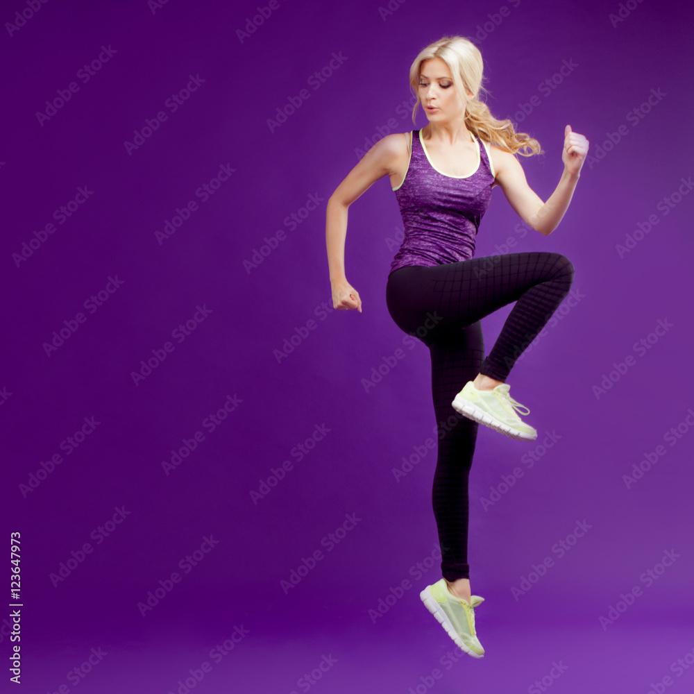 Beautiful young girl in a pose runner. Studio background, purple