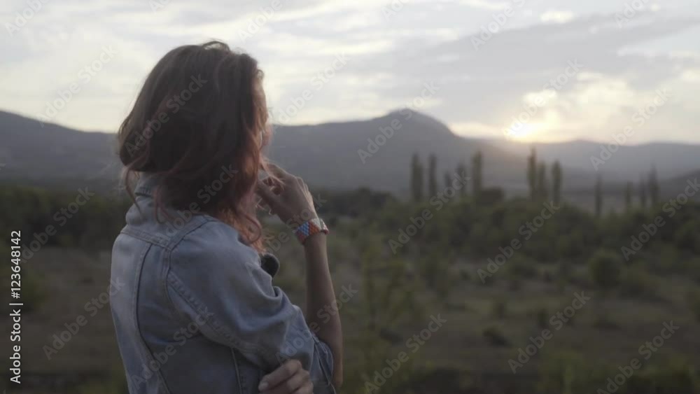 Thoughtful girl with pink hair in the dress standing in the mountainous area at sunset Thoughtful girl with pink hair in the dress standing in the mountainous area at sunset
