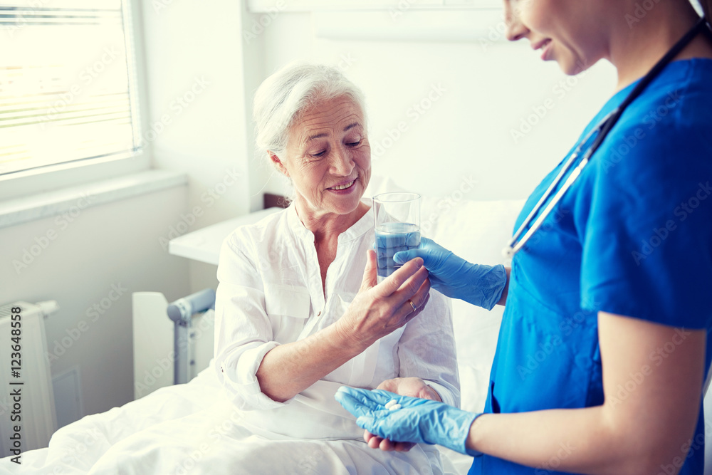 nurse giving medicine to senior woman at hospital nurse giving medicine to senior woman at hospital