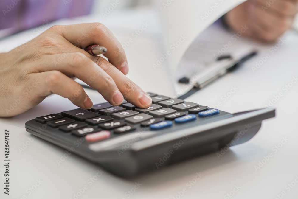 Photo of hands holding pencil and pressing calculator buttons Photo of hands holding pencil and pressing calculator buttons