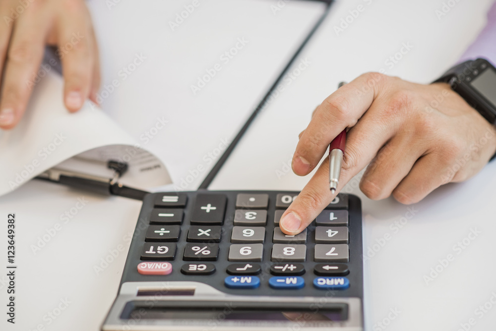 Close-up Of Businessman Calculating Invoices Using Calculator Close-up Of Businessman Calculating Invoices Using Calculator
