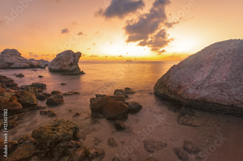 Φωτογραφία Sunset at rocky tropical coast, oil tanker at horizon, long exposure