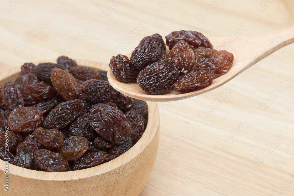 raisins in spoon with raisins in bowl. raisins in spoon with raisins in bowl.