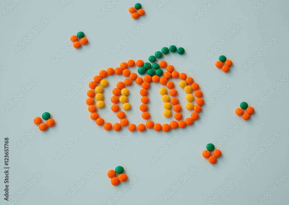 Symbol Halloween Holiday - a  yellow orange pumpkin made of small round candies. Isolated on a white background.