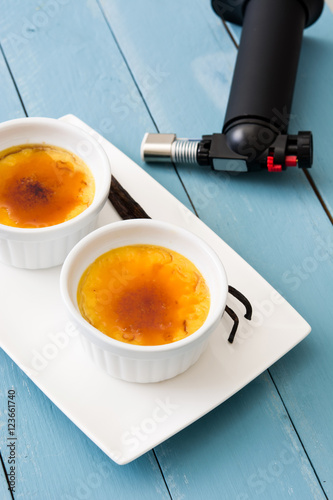 Tableau sur toile Traditional French creme brulee and blowtorch on blue wooden table
