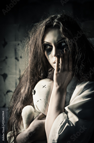 Canvas Print Horror style shot: strange sad girl with moppet doll in hands