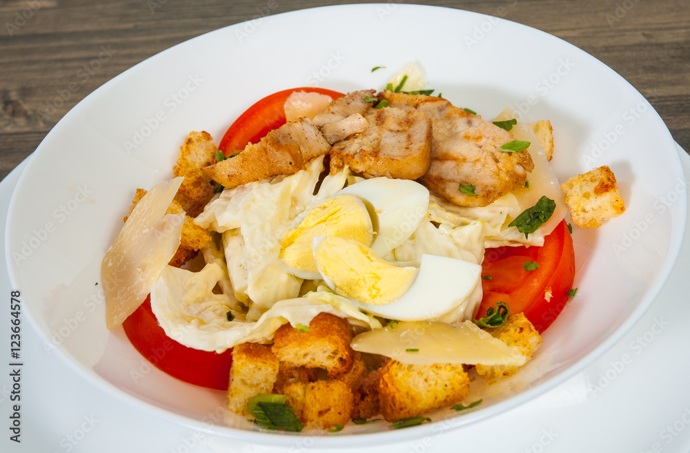 Caesar salad with croutons, cheese, eggs, tomatoes and grilled chicken on wooden table Caesar salad with croutons, cheese, eggs, tomatoes and grilled chicken on wooden table