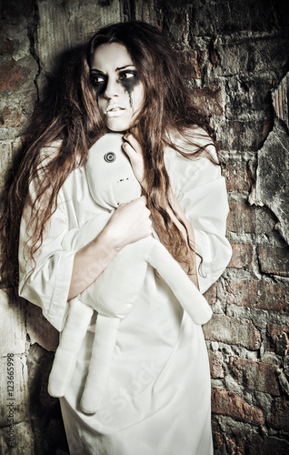 Horror scene: strange crazy girl with moppet doll in hands photo