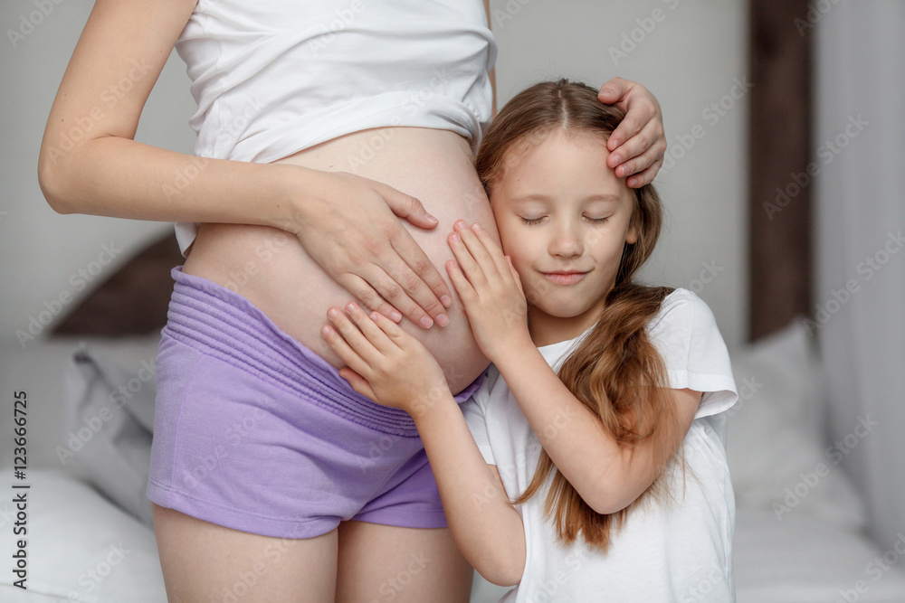 Cute little girl hugging belly of her pregnant mother, listening Cute little girl hugging belly of her pregnant mother, listening