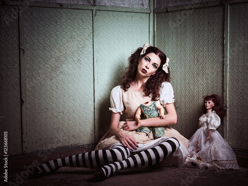Wallpaper Mural Strange sad girl with dolls sitting in forsaken place