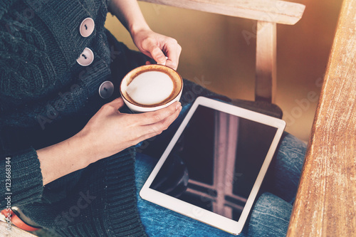 close up asian woman holding coffee and tablet in coffee shop wi