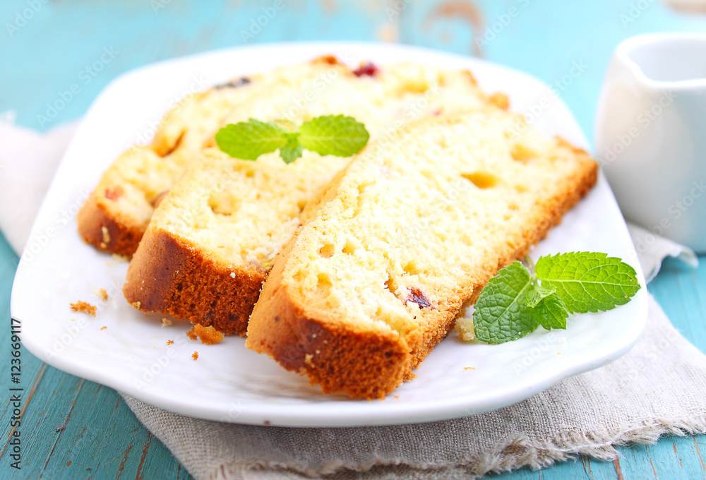 a piece of cake with raisins and candied fruit on a white plate on a blue background a piece of cake with raisins and candied fruit on a white plate on a blue background