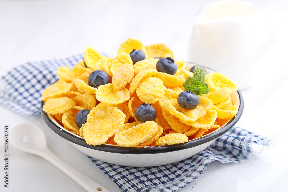 Cornflakes for breakfast with blueberries on a white background. Selective focus. Cornflakes for breakfast with blueberries on a white background. Selective focus.