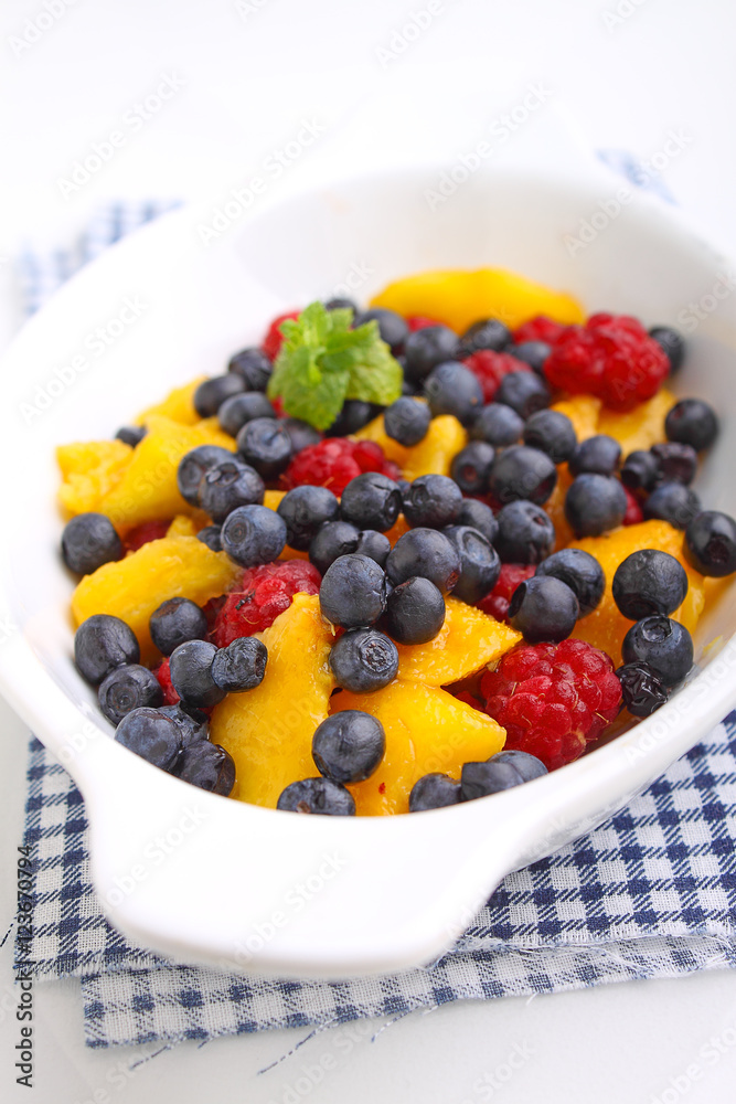 fresh berries in a white plate on a white background: raspberries, blueberries, peach. fresh berries in a white plate on a white background: raspberries, blueberries, peach.