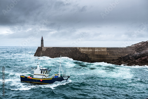 Fishing Vessel under Storm.arriving at pier. 
It's a boat or ship used to catch fish in the sea. Fishing can be affected by storms because of conditions like strong wind, precipitations or rain.

