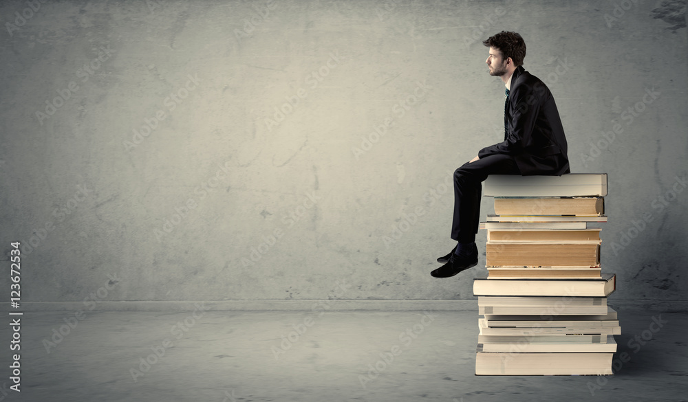 Student sitting on stack of books Student sitting on stack of books