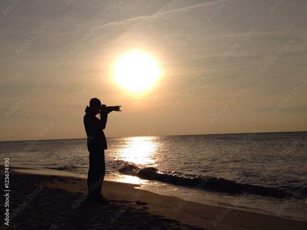 Silhouette eines Fotografen bei Sonnenuntergang am Meer