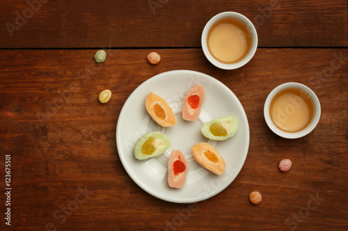 Colorful mochi rice cakes on white plate, porcelain cups with gr