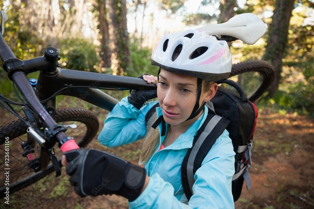 Female mountain biker carrying her bicycle in the forest Female mountain biker carrying her bicycle in the forest