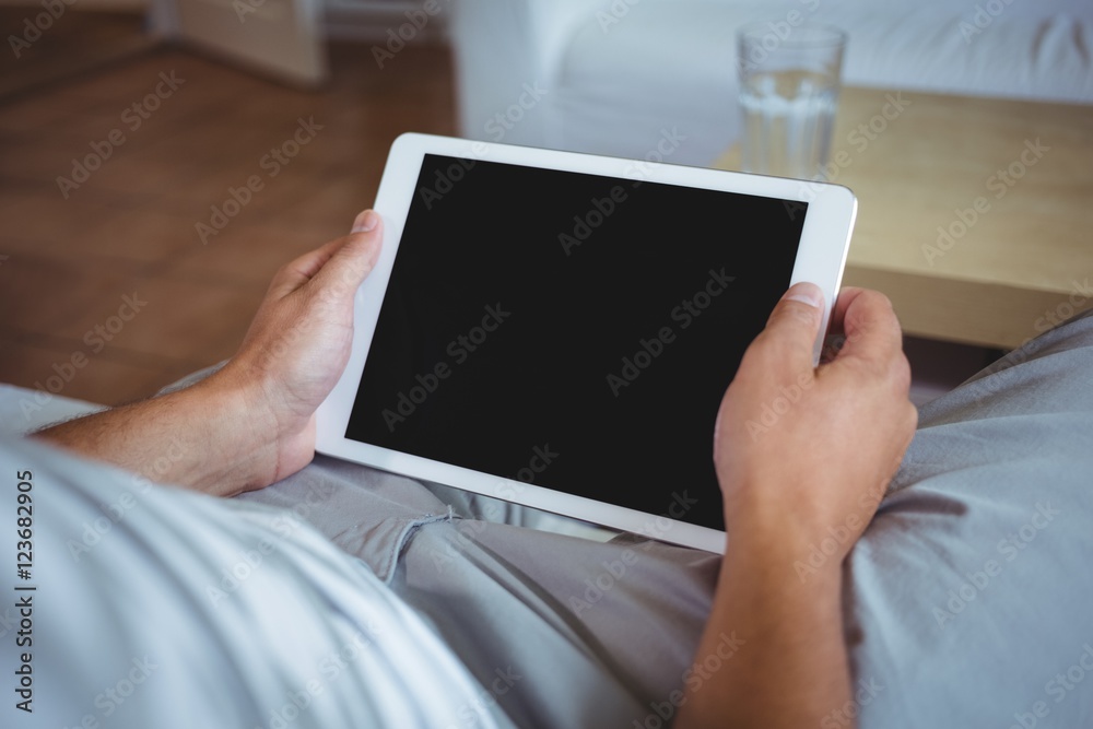 Mid section of man using digital tablet in living room Mid section of man using digital tablet in living room