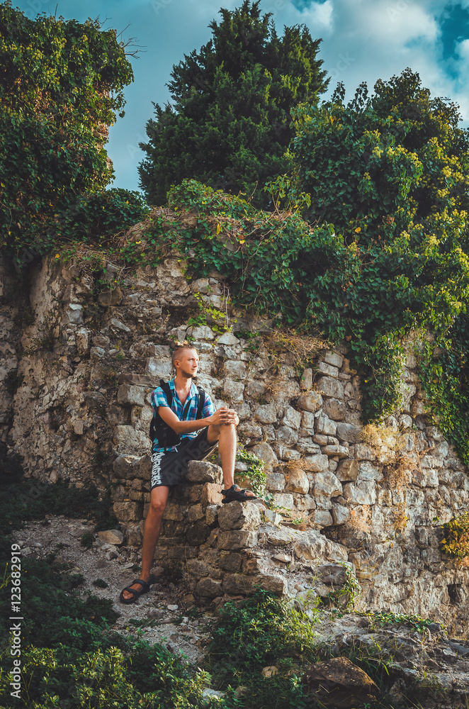 Handsome man in Stari Bar old fortress, Montenegro. Tanned male walking around ruins, tourism concept, lifestyle. Summer holidays, travel in Balkans.