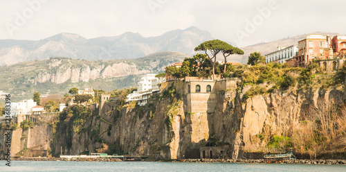 A sunlit cliff over Sorrento with trees and houses on top of it. photo