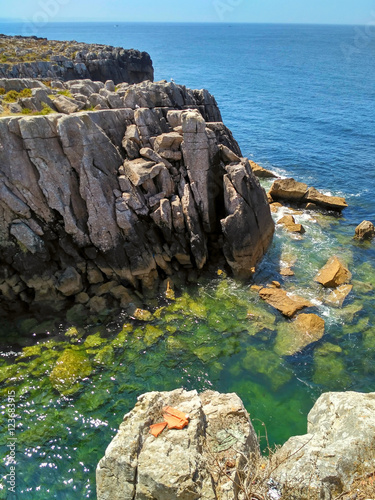 Foto Cliffs with rocks and amazing color water in ocean coast of Peniche