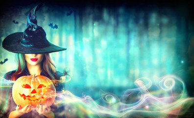 Sexy witch with a Halloween pumpkin Jack-o-lantern in a dark forest