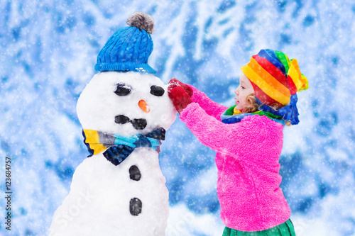 Little girl building a snow man in winter © famveldman