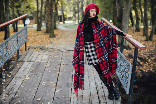 Beautiful happy girl in red hat and scarf walking in the autumn park