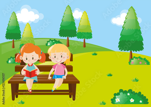 Two girls reading book in park