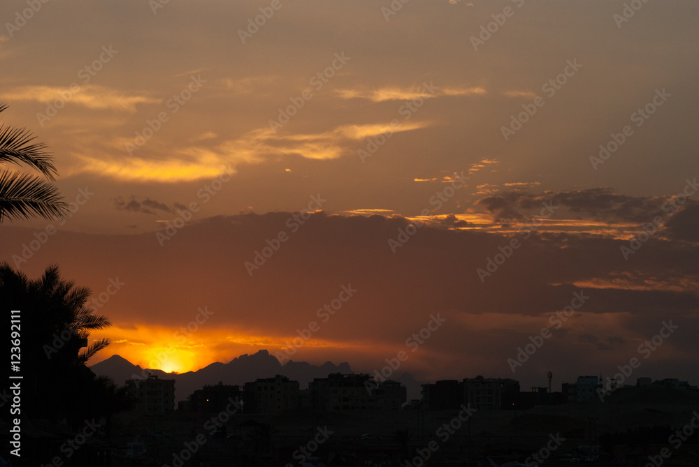 Sunset at city of Hurghada with buildings and mountains silhouette