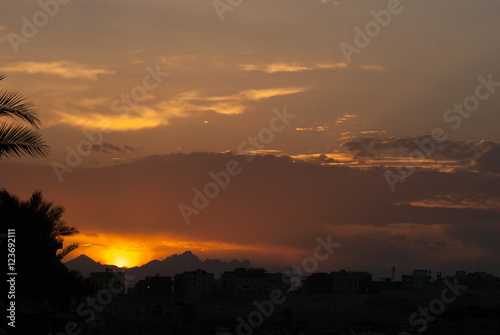 Sunset at city of Hurghada with buildings and mountains silhouette