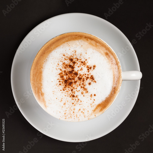 Hot cappuccino with cinnamon in a white cup.