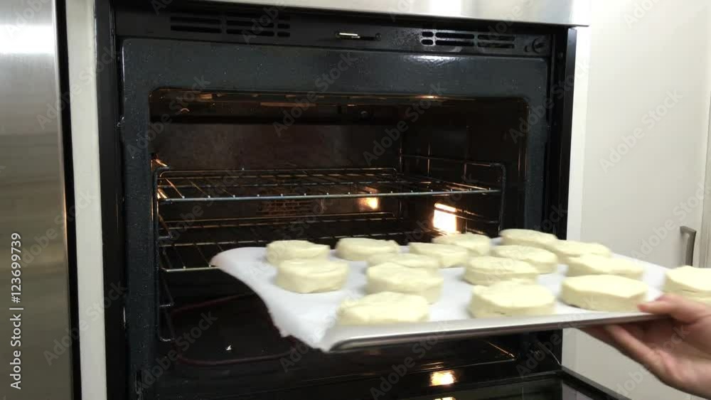 4K HD video of older female hands putting a tray of raw biscuit dough