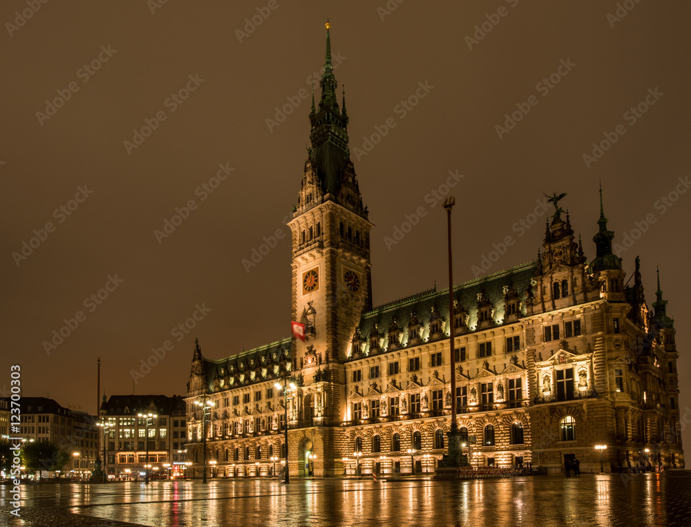golden leuchtendes Hamburger Rathaus bei Nacht   mit Spiegelung auf nassem Rathausplatz