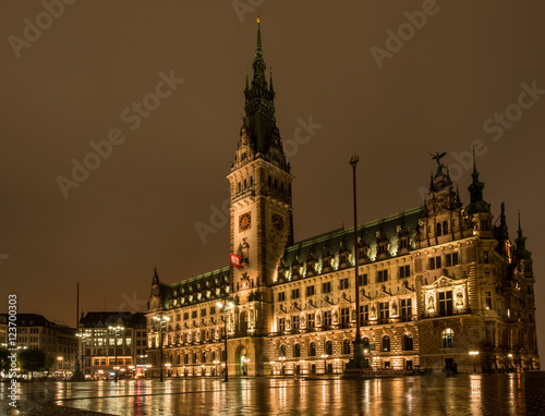 golden leuchtendes Hamburger Rathaus bei Nacht   mit Spiegelung auf nassem Rathausplatz